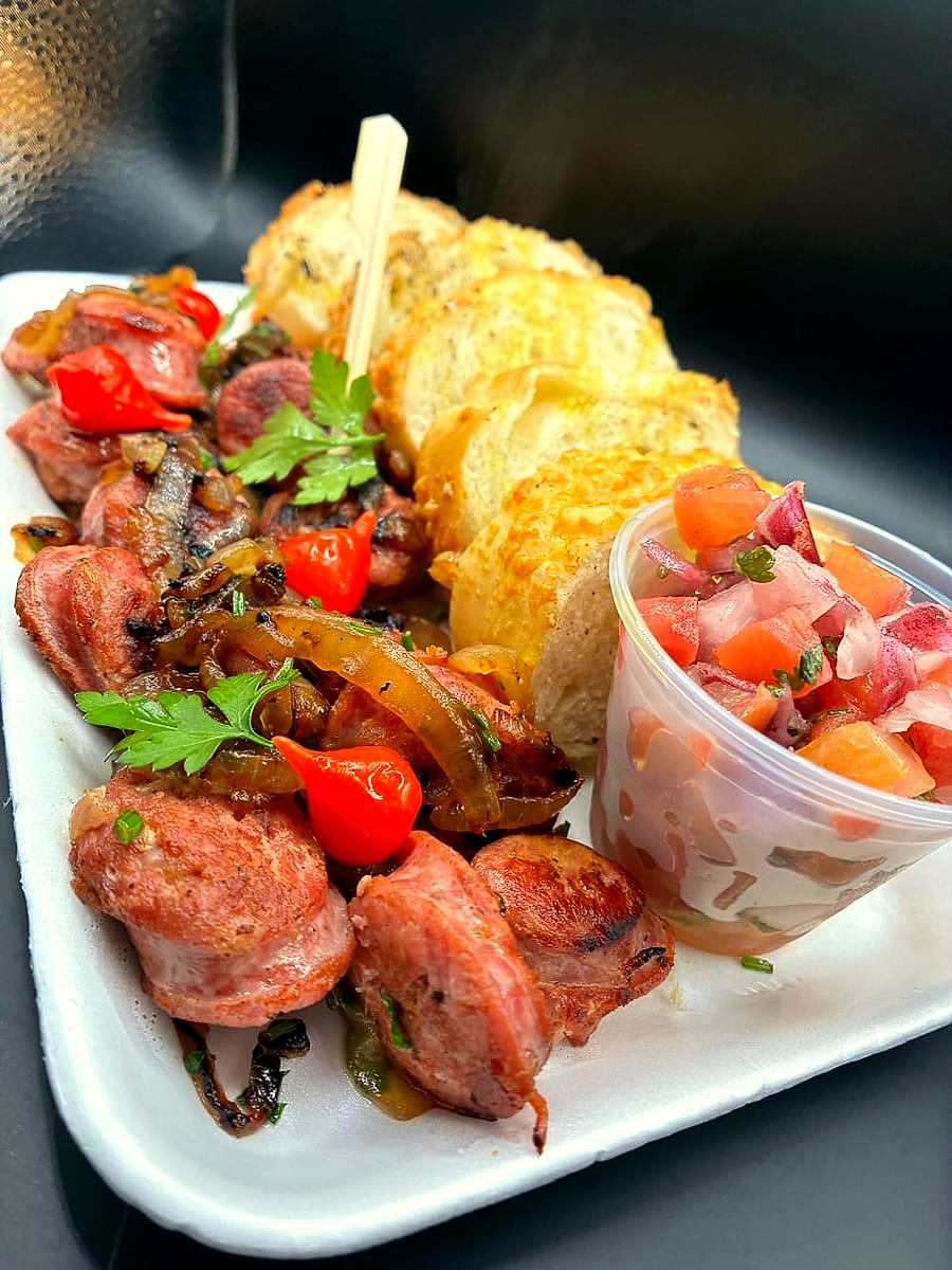 Porção de linguiça com cebola, pimenta biquinho e pão de alho